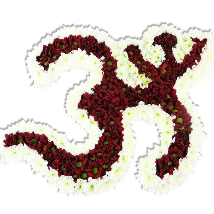 From our Charlton studio near Charlton Park, this handcrafted floral Om is presented against an immaculate white background that makes every petal and contour read clearly. The main form-the classic '3'-shaped curve, the softly hooked descending stroke, and the small crescent-and-dot above-is composed of tightly set maroon and deep burgundy chrysanthemum-like blooms, each with a little lime-green eye that adds unexpected vitality to the dark field. Encircling and accentuating the emblem is a thick, flowing border of snow-white spray chrysanthemums; their delicate, layered petals create a crisp architectural edge that both frames and breathes around the red interior. The arrangement's dense packing gives it a plush, tactile surface, while the white outline defines the negative spaces and lends a calm, luminous contrast. Subtle studio lighting creates a soft drop shadow beneath the piece, emphasising its three-dimensional sculptural quality as though the Om were raised slightly from the white plane. One senses a quiet, grounding perfume-an earthy, late-summer floral aroma-that complements the arrangement's reverent mood. Locally, this design resonates with families and community groups across Charlton and neighbouring Woolwich and Greenwich who seek a visually powerful, respectful emblem for spiritual ceremonies, cultural festivals, or moments of remembrance; its craftsmanship reflects the steady hand of experienced florists in the area.